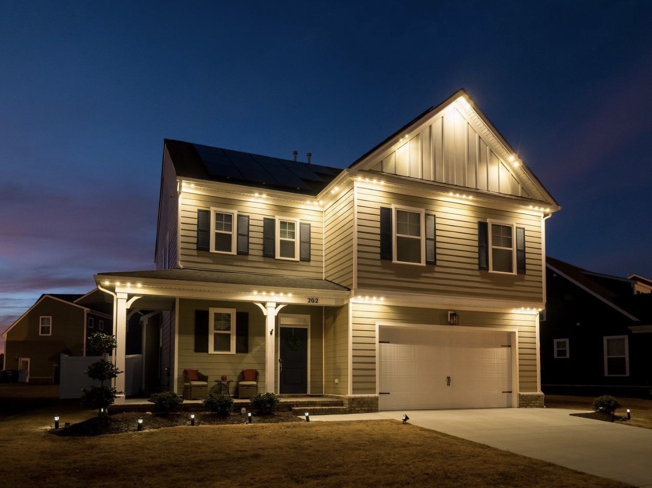 Two-story residential home with warm-white permanent exterior lighting