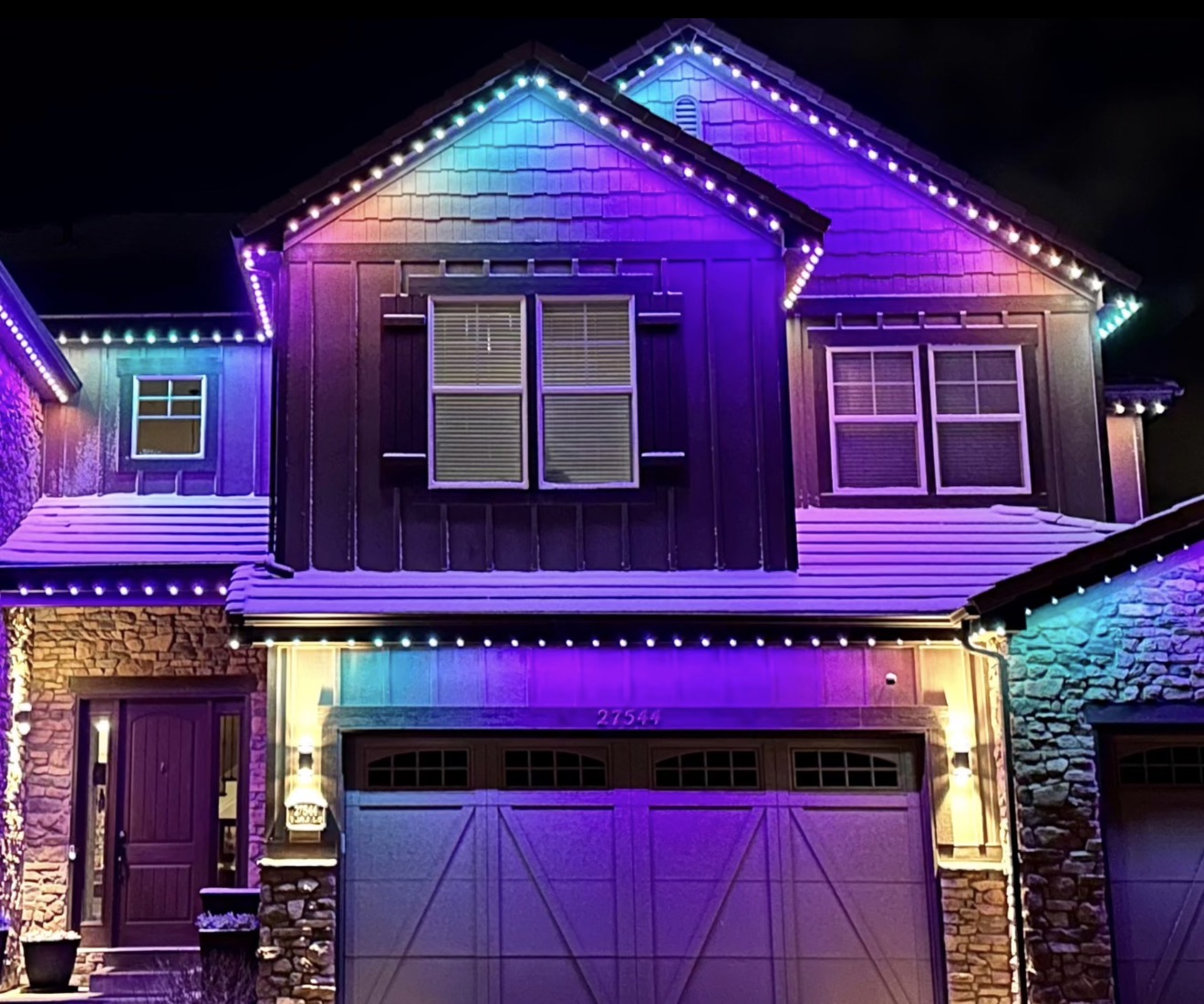 Permanent lights casting a colorful downward wash across a home's exterior