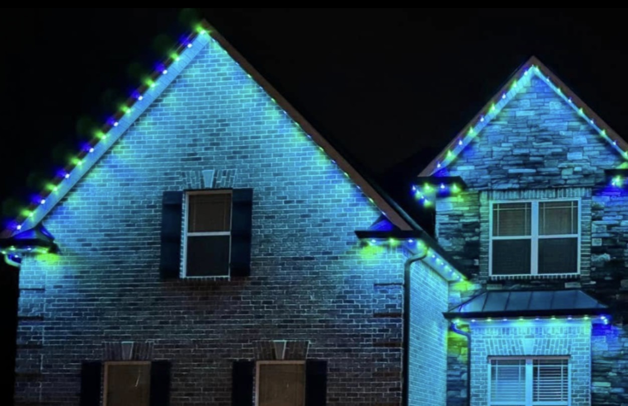 Brick and stone home accented with blue and green permanent lighting